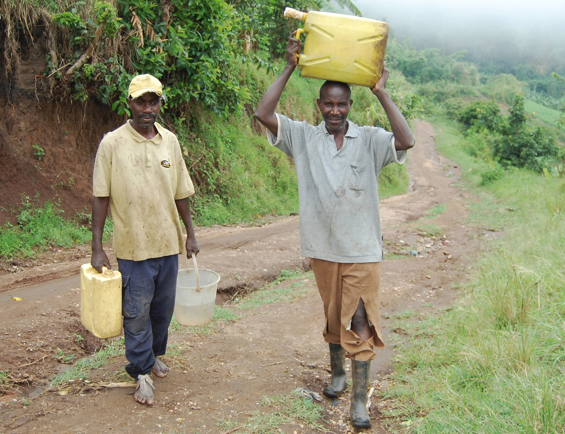 Pius Masereka und Exavier Bwanandeke tragen die Wasserkanister zur Waschstation (v.l.n.r.)